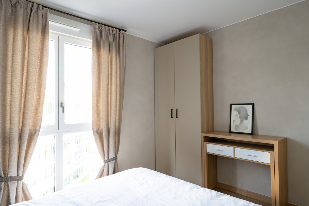 Diseño de dormitorio principal actual con paredes beige y suelo de madera clara