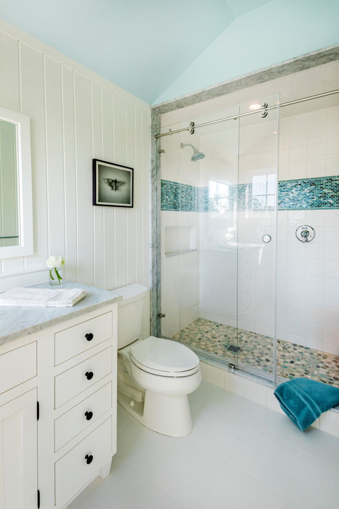 This is an example of a medium sized coastal ensuite bathroom in Boston with beaded cabinets, white cabinets, an alcove shower, a two-piece toilet, white tiles, ceramic tiles, white walls, laminate floors, a submerged sink, marble worktops, white floors, a sliding door, yellow worktops, a wall niche, a single sink, a freestanding vanity unit and tongue and groove walls.