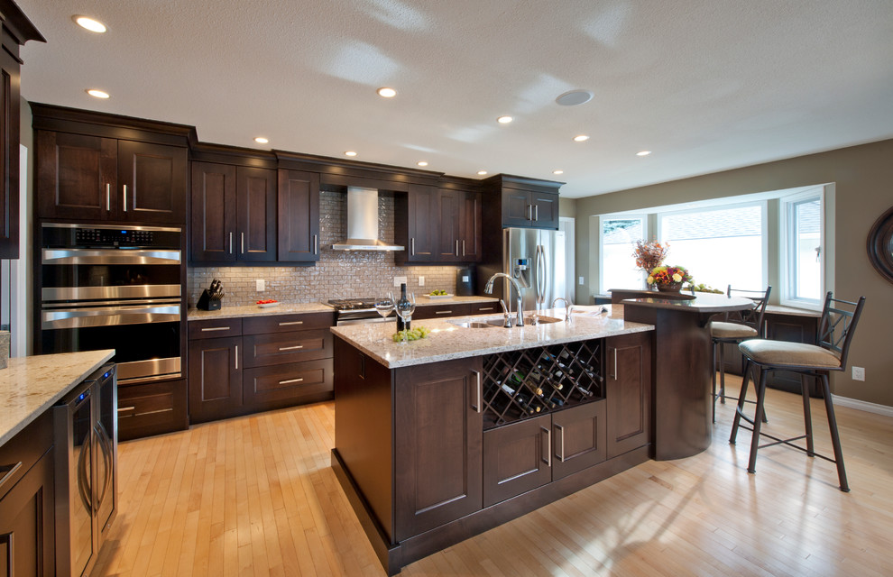 Eat-in kitchen - large u-shaped light wood floor eat-in kitchen idea in Vancouver with an undermount sink, recessed-panel cabinets, dark wood cabinets, glass tile backsplash, stainless steel appliances and an island