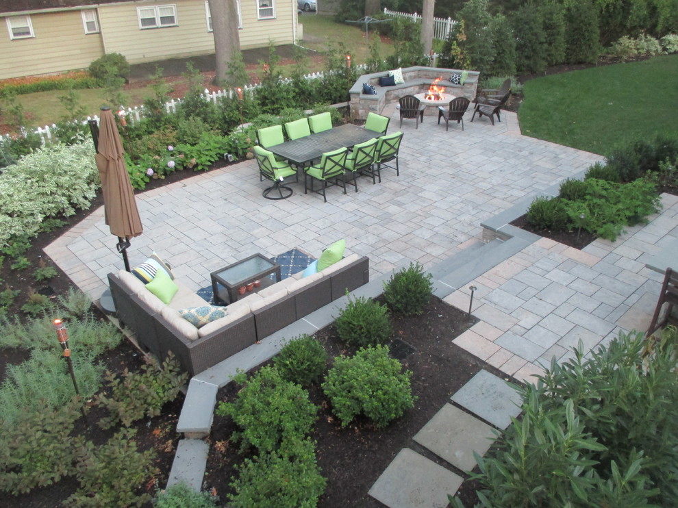 Large traditional backyard patio in New York with a fire feature, natural stone pavers and no cover.