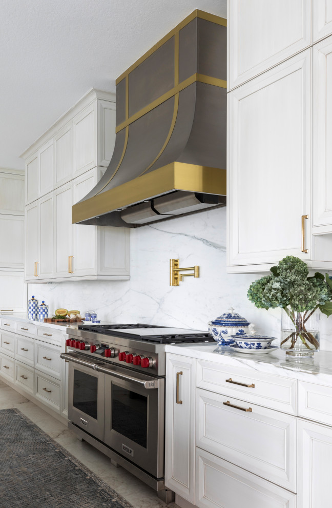 Inspiration for a large transitional l-shaped eat-in kitchen in Houston with a farmhouse sink, recessed-panel cabinets, white cabinets, marble benchtops, white splashback, stone slab splashback, panelled appliances, porcelain floors, with island, white floor and white benchtop.