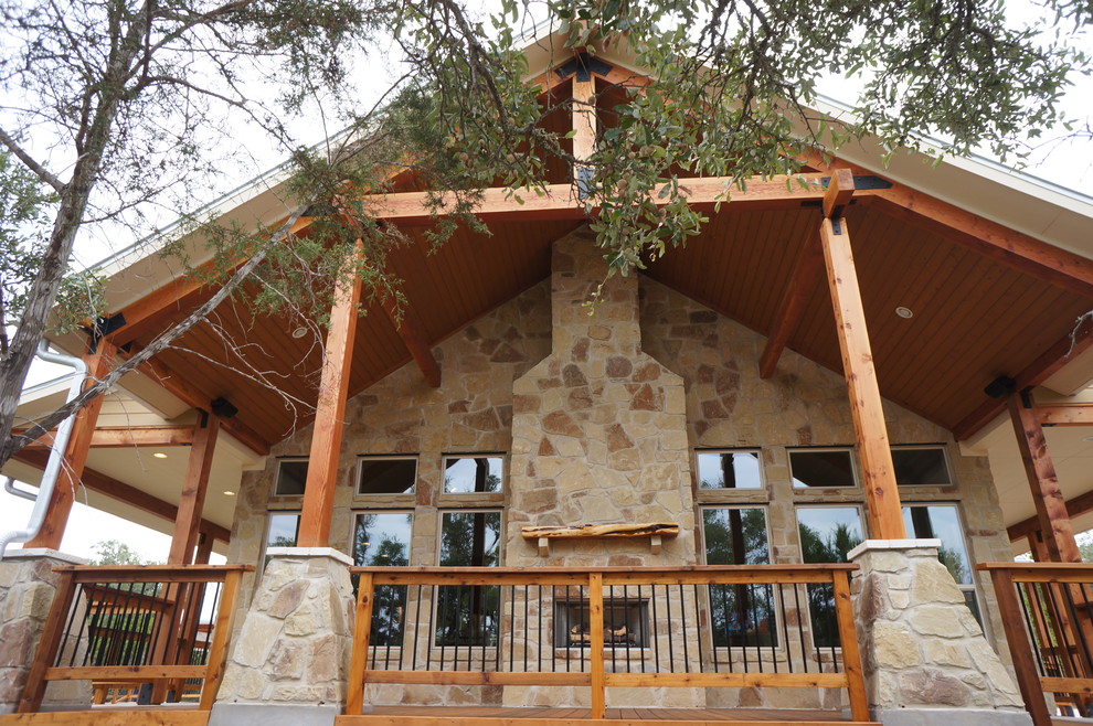 This is an example of a large country one-storey black exterior in Austin with stone veneer and a gambrel roof.