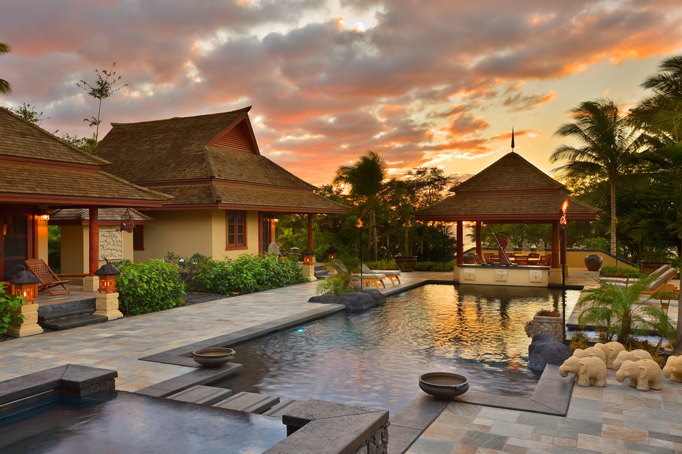 Photo of a mid-sized asian rectangular infinity pool in Hawaii with a hot tub and natural stone pavers.