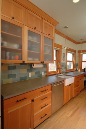 Kitchen pantry - mid-sized transitional galley medium tone wood floor kitchen pantry idea in Seattle with a farmhouse sink, glass-front cabinets, medium tone wood cabinets, wood countertops, multicolored backsplash, glass tile backsplash, stainless steel appliances, gray walls and an island