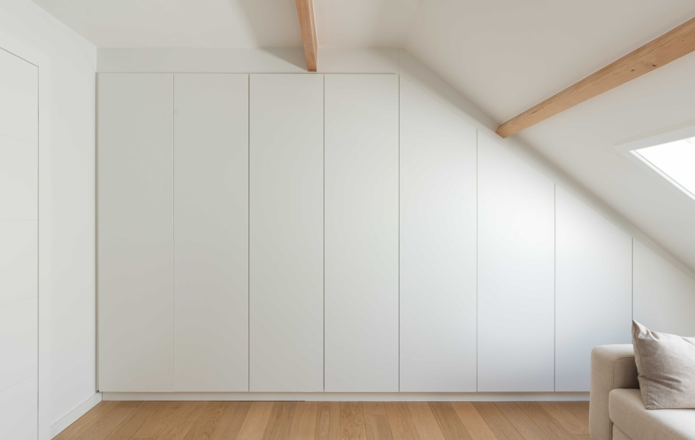Foto de dormitorio tipo loft escandinavo de tamaño medio con paredes blancas, suelo de madera clara y vigas vistas