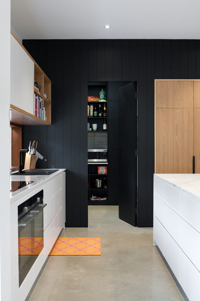 Photo of a mid-sized scandinavian galley kitchen pantry in Adelaide with a drop-in sink, quartz benchtops, window splashback, black appliances, concrete floors and with island.