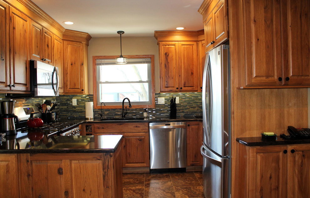 Mid-sized mountain style u-shaped kitchen photo with raised-panel cabinets, medium tone wood cabinets, quartz countertops, stone tile backsplash and stainless steel appliances