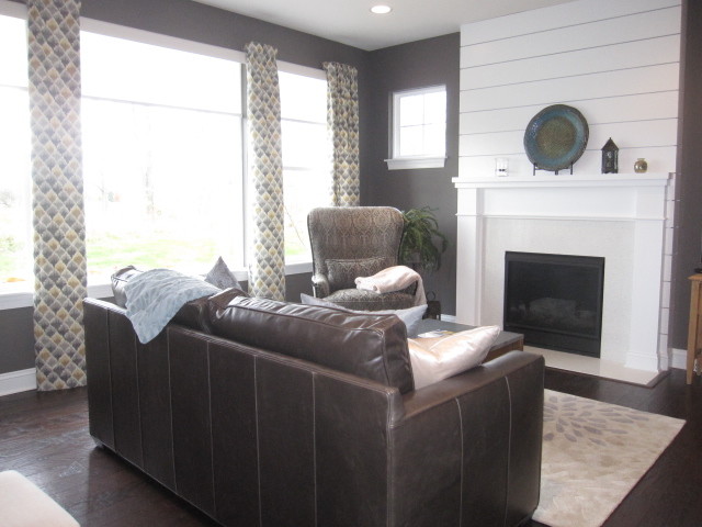 This is an example of a small country open concept family room in Cleveland with grey walls, dark hardwood floors, a standard fireplace, a stone fireplace surround, a wall-mounted tv and brown floor.