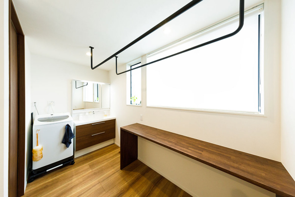 Inspiration for a mid-sized industrial l-shaped utility room in Tokyo Suburbs with white walls, dark hardwood floors, brown floor, brown benchtop, wallpaper and wallpaper.