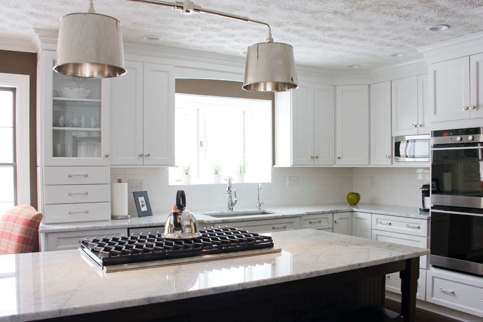Example of a large transitional l-shaped dark wood floor kitchen design with an undermount sink, shaker cabinets, white cabinets, marble countertops, white backsplash, stainless steel appliances and an island