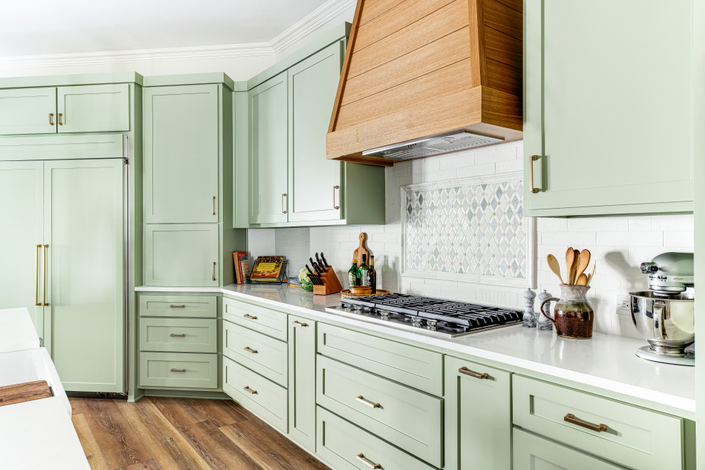 This is an example of a large country kitchen in Dallas with a farmhouse sink, shaker cabinets, green cabinets, quartz benchtops, white splashback, ceramic splashback, stainless steel appliances, multiple islands, brown floor and white benchtop.