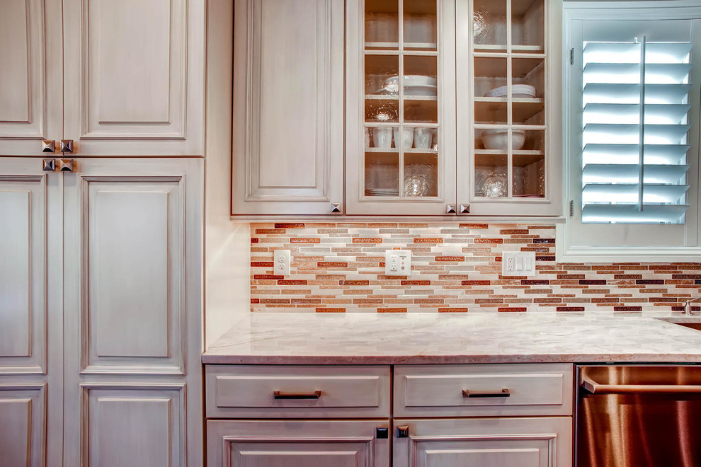 This is an example of a large traditional l-shaped eat-in kitchen in Denver with an undermount sink, raised-panel cabinets, white cabinets, quartz benchtops, metallic splashback, matchstick tile splashback, stainless steel appliances, medium hardwood floors and with island.