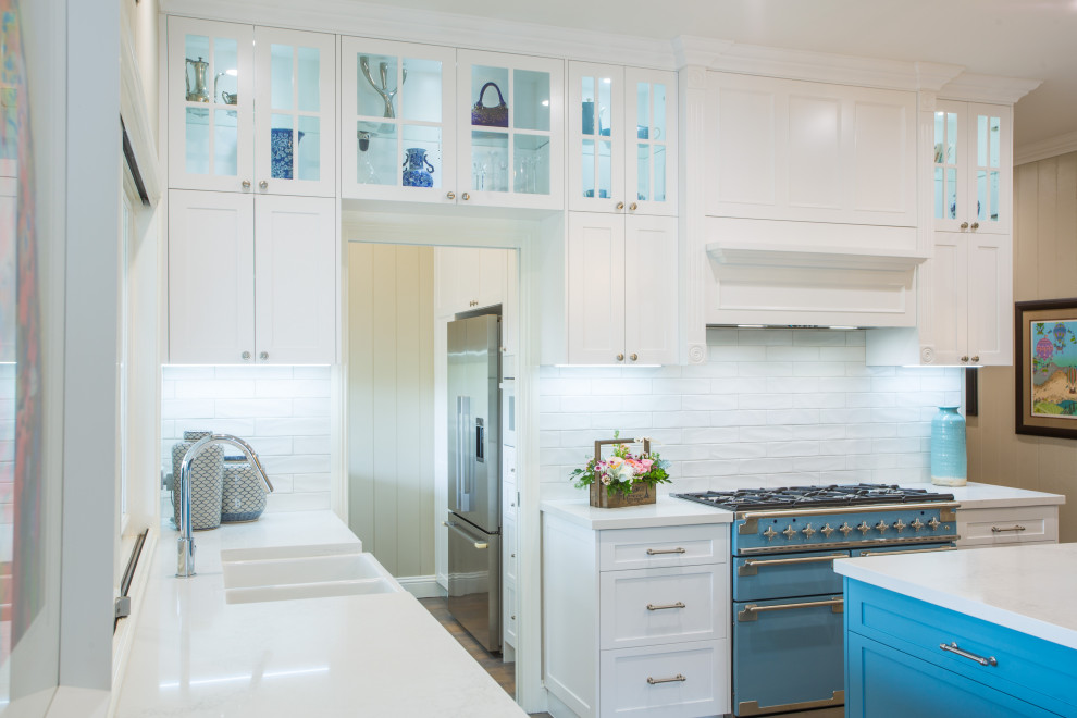 Design ideas for an expansive traditional l-shaped kitchen pantry in Brisbane with a farmhouse sink, shaker cabinets, white cabinets, quartz benchtops, white splashback, subway tile splashback, coloured appliances, medium hardwood floors, with island and white benchtop.