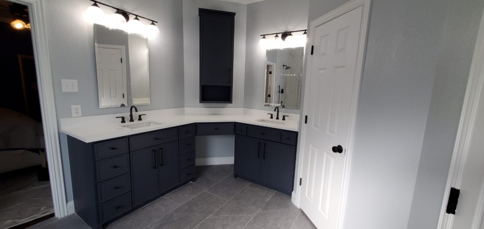 Design ideas for a medium sized modern ensuite bathroom in Dallas with shaker cabinets, black cabinets, a freestanding bath, a corner shower, a two-piece toilet, white tiles, marble tiles, blue walls, ceramic flooring, a submerged sink, grey floors, a hinged door, white worktops, double sinks, a built in vanity unit and an enclosed toilet.