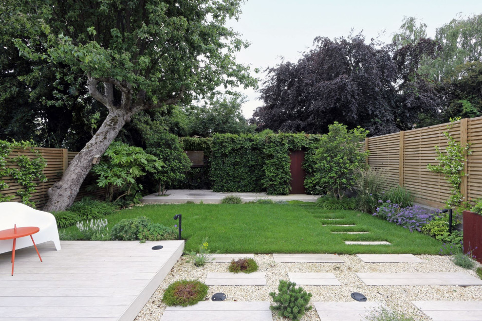 Design ideas for a large modern back formal partial sun garden for summer in London with a living wall, decking and a wood fence.