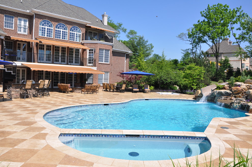 Photo of a large traditional backyard custom-shaped pool in Philadelphia with a water slide and tile.