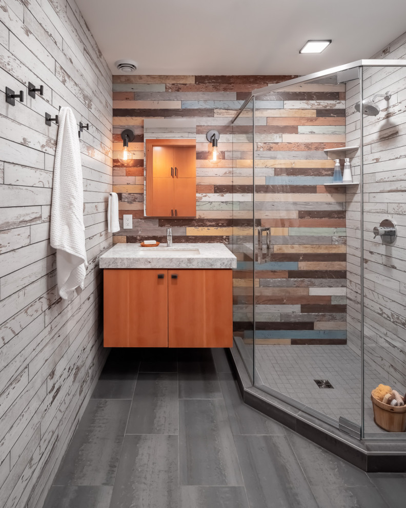 Design ideas for a medium sized rustic shower room bathroom in Minneapolis with flat-panel cabinets, medium wood cabinets, a corner shower, a one-piece toilet, multi-coloured tiles, wood-effect tiles, multi-coloured walls, porcelain flooring, a submerged sink, engineered stone worktops, grey floors, a hinged door, white worktops, a single sink and a floating vanity unit.