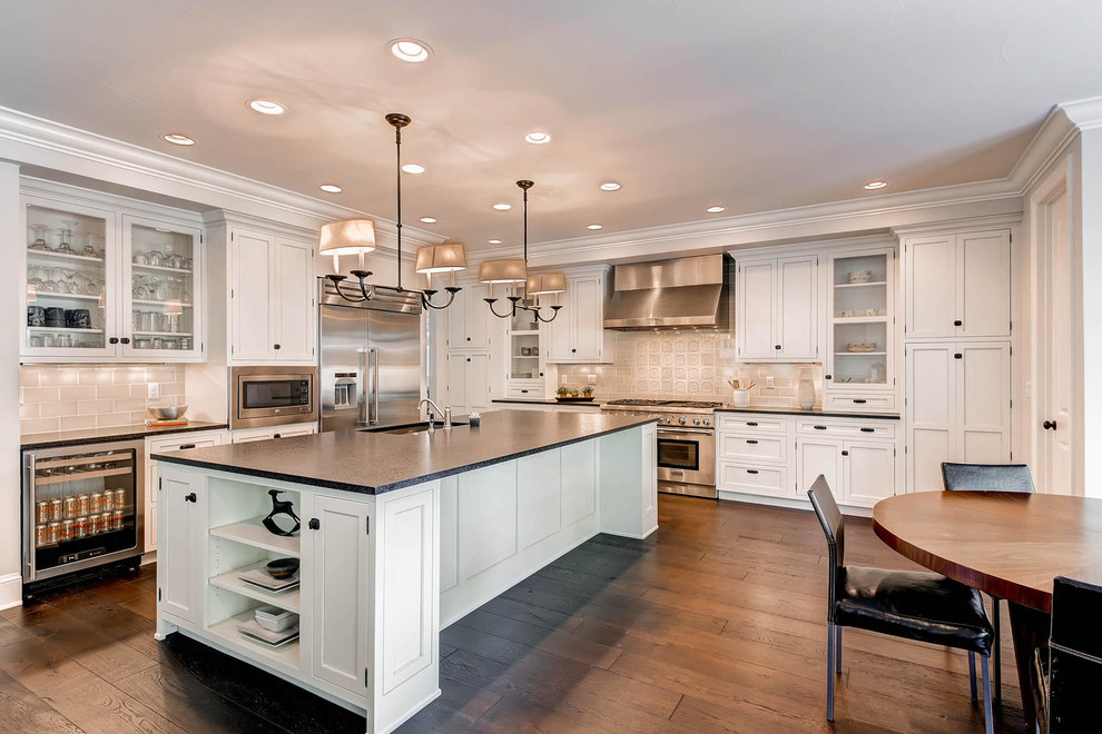 Mid-sized transitional l-shaped eat-in kitchen in Denver with an undermount sink, shaker cabinets, white cabinets, solid surface benchtops, beige splashback, porcelain splashback, stainless steel appliances, medium hardwood floors and with island.