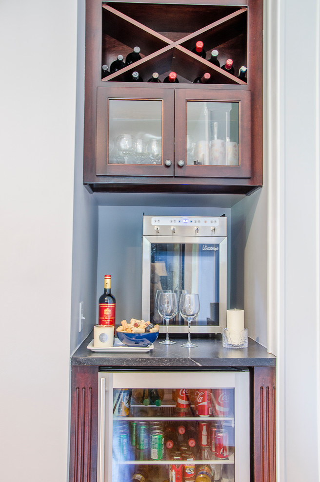 Inspiration for a small country single-wall home bar in Richmond with glass-front cabinets, dark wood cabinets and soapstone benchtops.