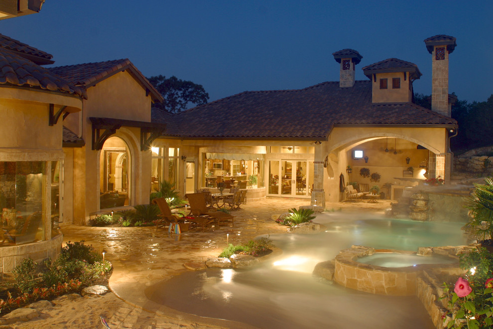 Large beach style backyard stone and custom-shaped hot tub photo in Austin