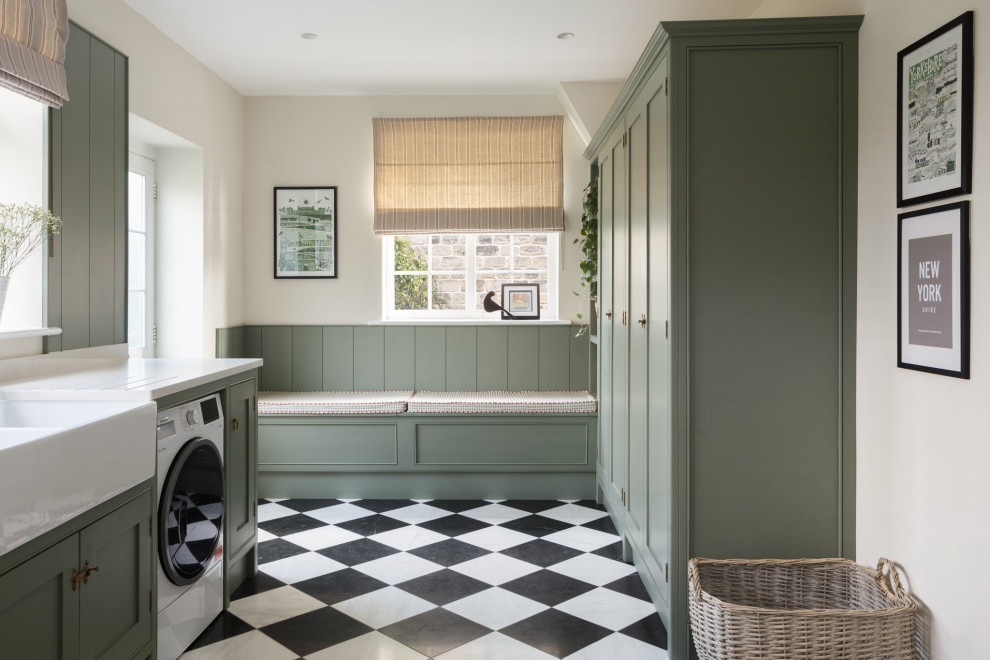 Traditional utility room in Other with a belfast sink, shaker cabinets, green cabinets, quartz worktops, white walls, ceramic flooring, a side by side washer and dryer, black floors, white worktops and panelled walls.