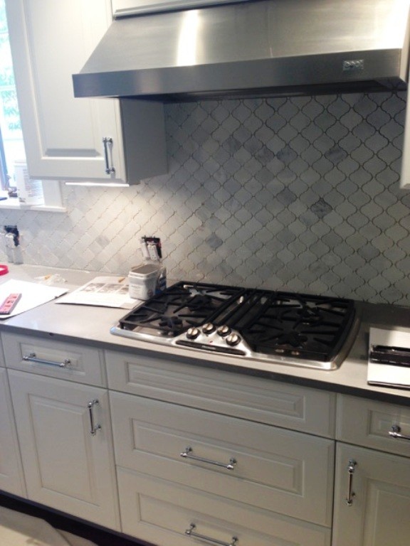 Photo of a modern kitchen in Chicago with quartz benchtops, white splashback, stone tile splashback, stainless steel appliances and with island.