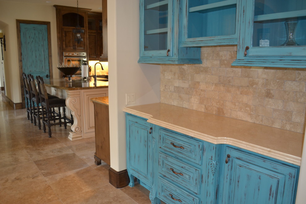 Photo of a large mediterranean u-shaped eat-in kitchen in Houston with an undermount sink, raised-panel cabinets, distressed cabinets, marble benchtops, beige splashback, stone tile splashback, stainless steel appliances, with island and medium hardwood floors.