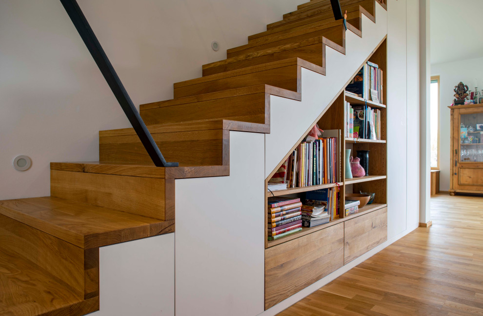Modelo de escalera recta actual con escalones de madera, contrahuellas de madera y barandilla de metal