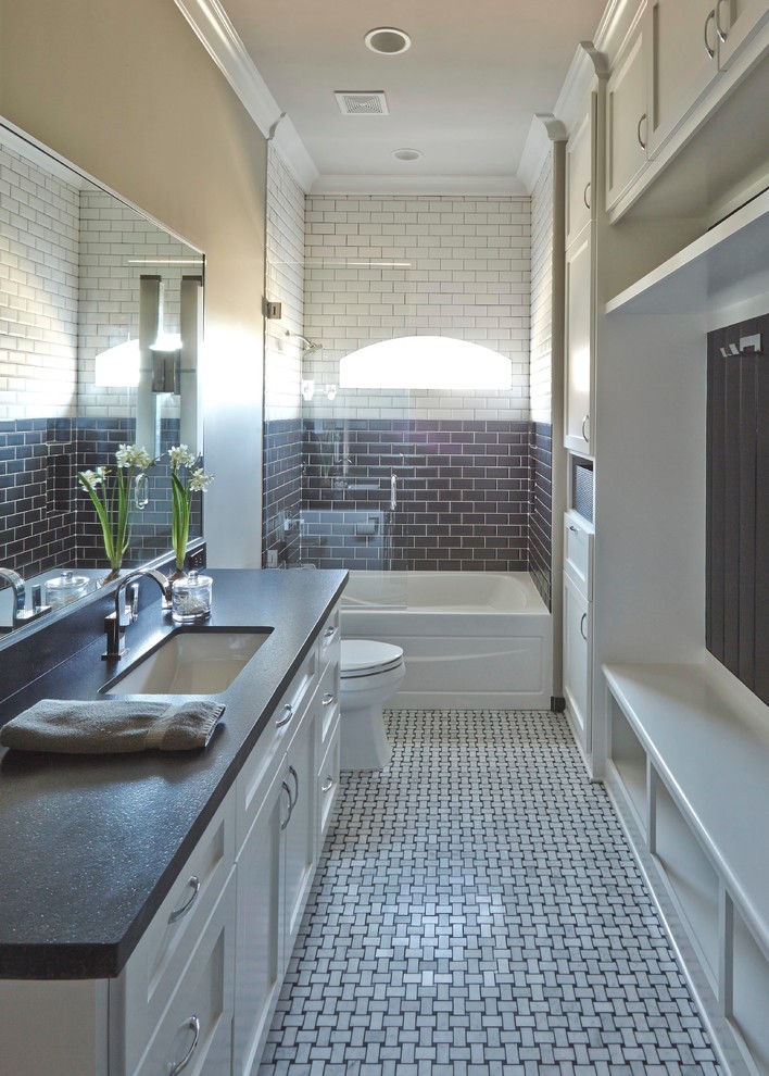 Design ideas for a mid-sized transitional kids bathroom in Other with raised-panel cabinets, white cabinets, an alcove tub, an alcove shower, a one-piece toilet, gray tile, subway tile, beige walls, mosaic tile floors, a drop-in sink, quartzite benchtops, white floor, a hinged shower door, black benchtops, a laundry, a single vanity and a built-in vanity.