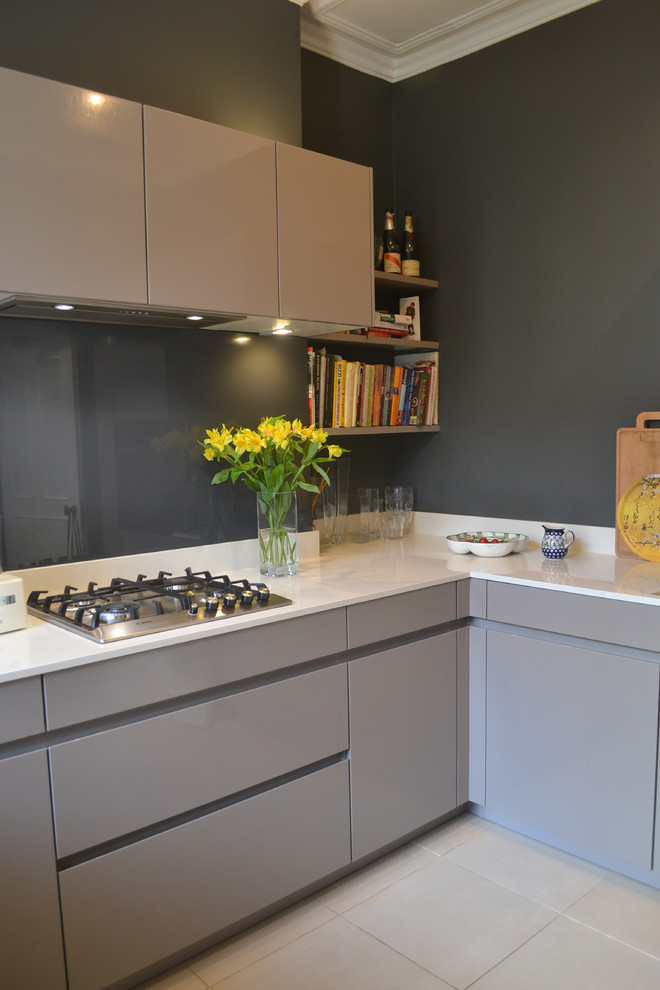 This is an example of a small contemporary u-shaped separate kitchen in London with an undermount sink, flat-panel cabinets, grey cabinets, laminate benchtops, grey splashback, glass sheet splashback and black appliances.