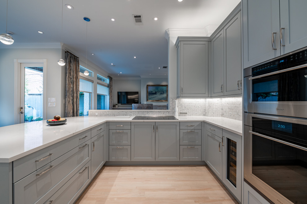 Eat-in kitchen - large transitional u-shaped light wood floor and beige floor eat-in kitchen idea in Houston with an undermount sink, shaker cabinets, gray cabinets, quartz countertops, ceramic backsplash, stainless steel appliances and white countertops