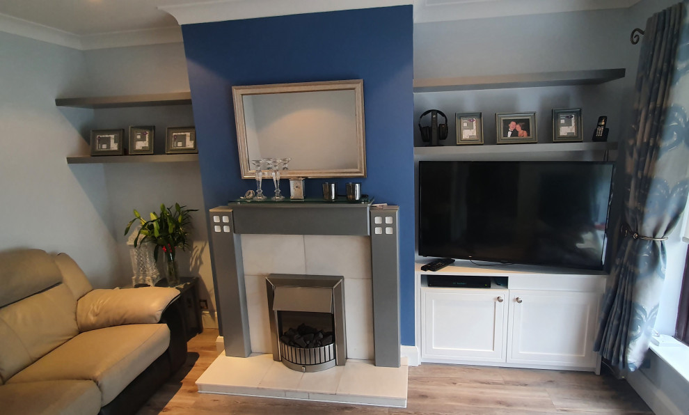 This is an example of a mid-sized modern formal open concept living room in Dublin with grey walls, laminate floors, a standard fireplace, a wall-mounted tv and multi-coloured floor.