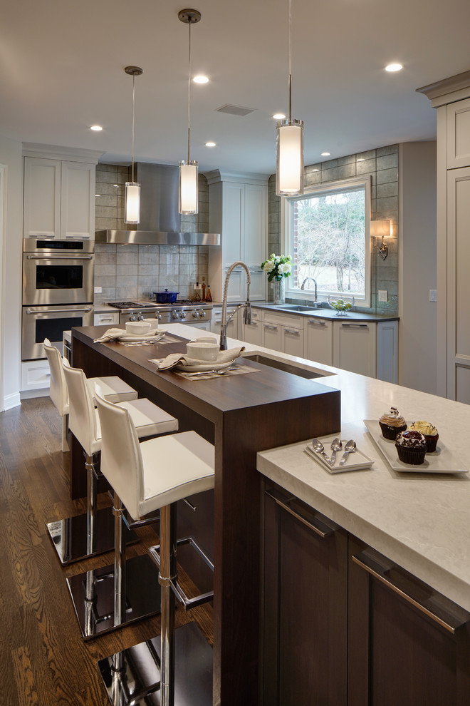 Inspiration for a large transitional u-shaped eat-in kitchen in Chicago with an undermount sink, shaker cabinets, dark wood cabinets, wood benchtops, metallic splashback, glass tile splashback, stainless steel appliances, dark hardwood floors, with island and brown floor.