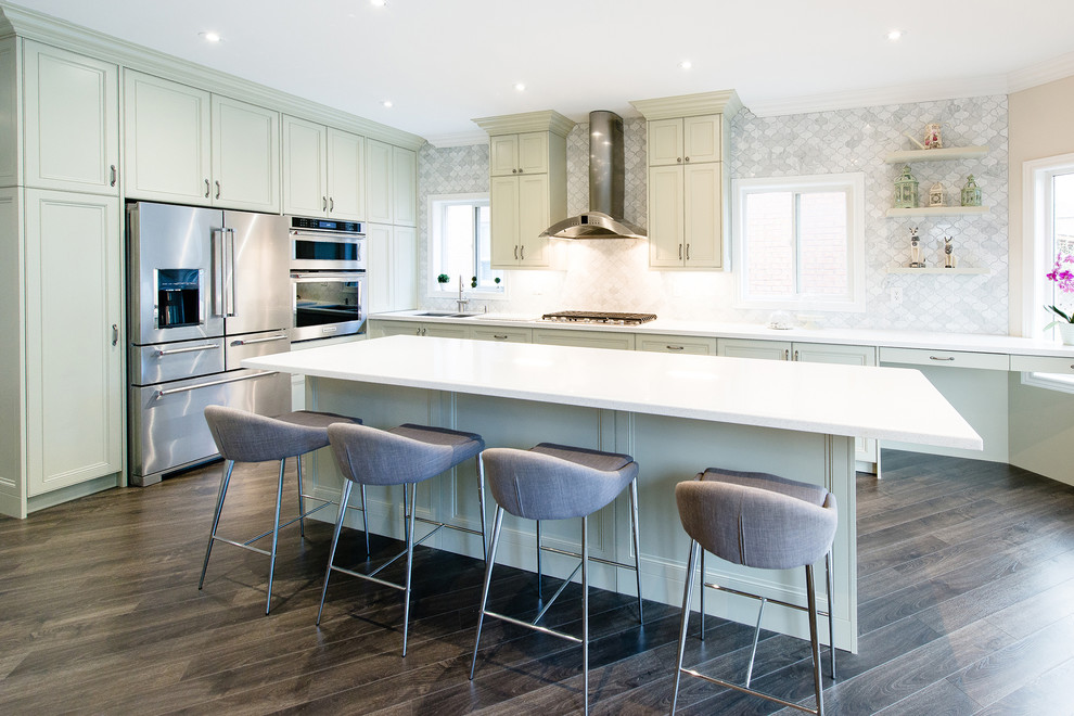 Large transitional l-shaped kitchen pantry in Toronto with a double-bowl sink, green cabinets, quartz benchtops, grey splashback, stone tile splashback, stainless steel appliances, medium hardwood floors and with island.