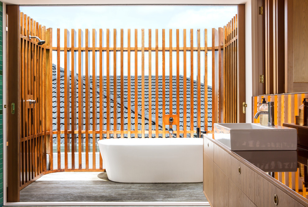 Photo of a contemporary master bathroom in Auckland with flat-panel cabinets, a freestanding tub, an open shower, a vessel sink, an open shower and brown benchtops.