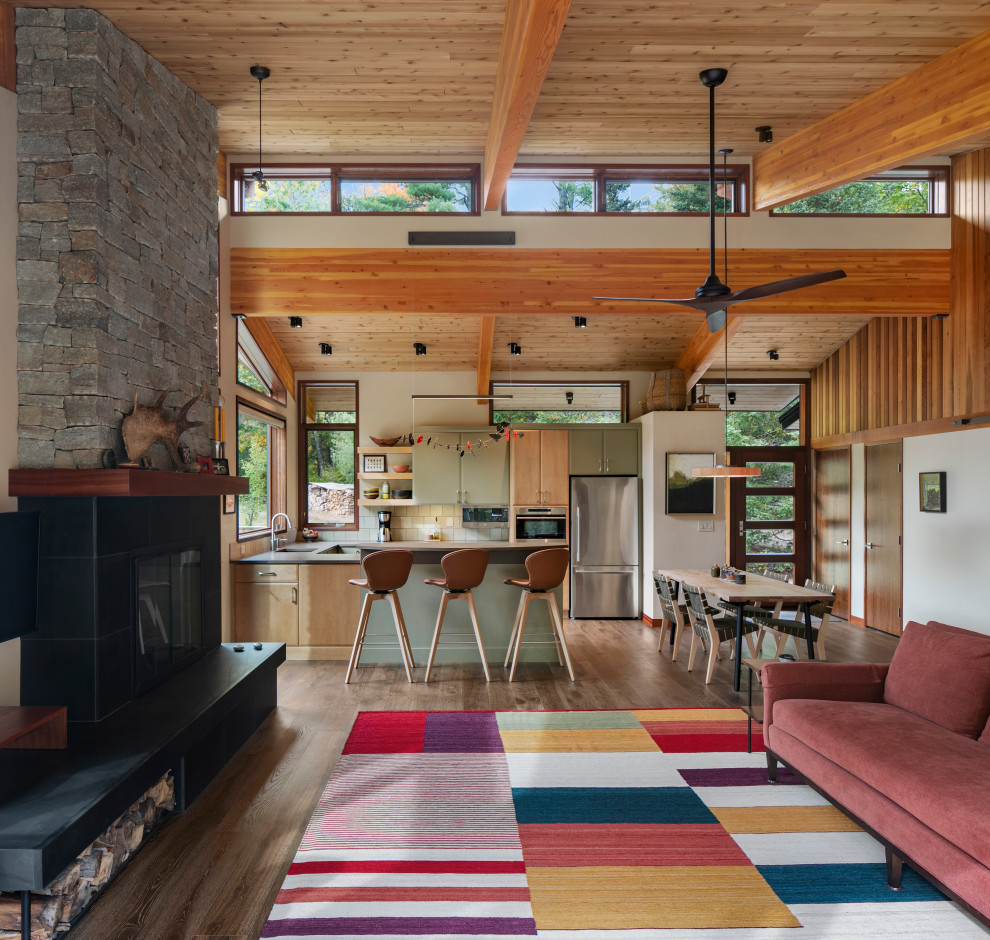 Photo of a mid-sized midcentury open concept living room in Manchester with white walls, medium hardwood floors, a standard fireplace, a tile fireplace surround and a wall-mounted tv.