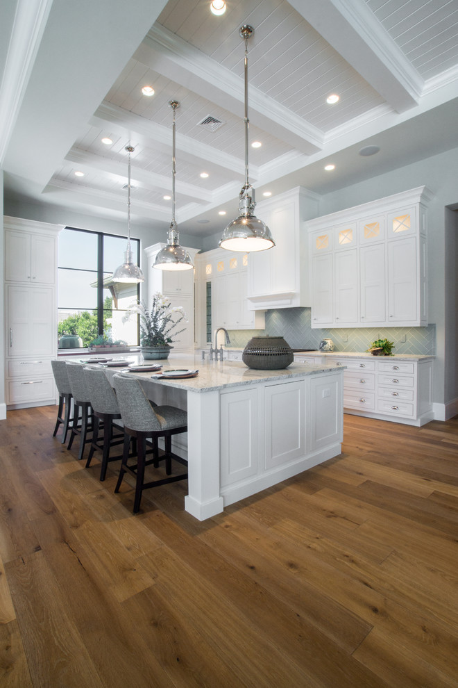 Example of a large transitional l-shaped eat-in kitchen design in Miami with shaker cabinets, white cabinets, granite countertops, green backsplash and an island
