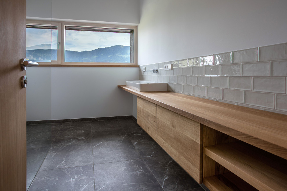 Modernes Badezimmer mit hellbraunen Holzschränken, grauem Boden, Einzelwaschbecken, bodengleicher Dusche und Aufsatzwaschbecken in München