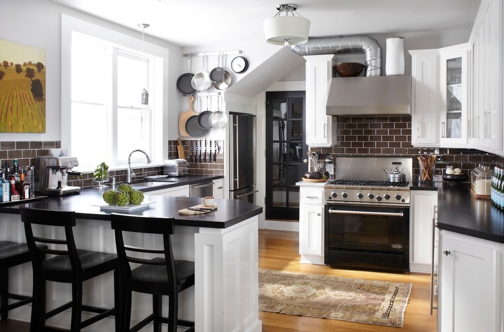 Photo of a traditional u-shaped eat-in kitchen in San Francisco with an undermount sink, shaker cabinets, white cabinets, granite benchtops, brown splashback, subway tile splashback and black appliances.