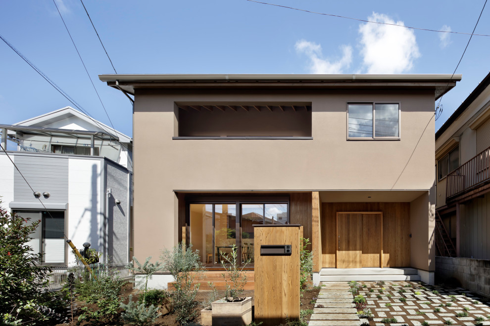 Cette image montre une façade de maison marron de taille moyenne et à un étage avec un toit à deux pans, un toit en tuile et un toit noir.