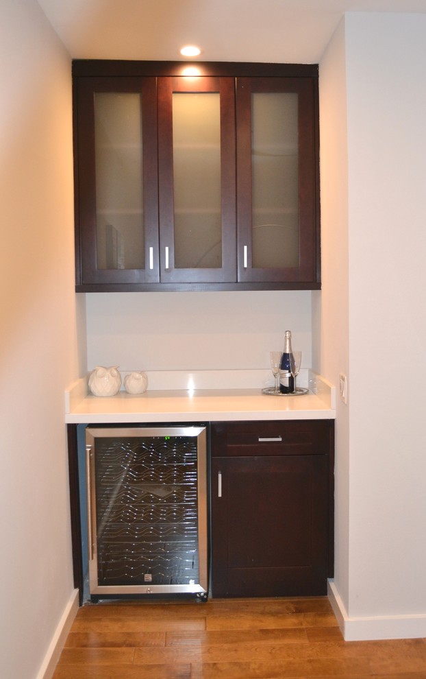 Design ideas for a small modern single-wall wet bar in Los Angeles with shaker cabinets, brown cabinets and solid surface benchtops.
