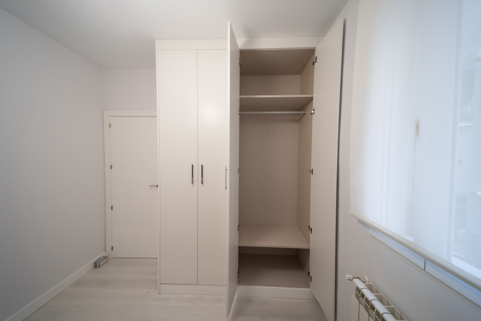 Cette photo montre une armoire encastrée scandinave en bois clair de taille moyenne et neutre avec un placard avec porte à panneau encastré, parquet clair et un sol gris.