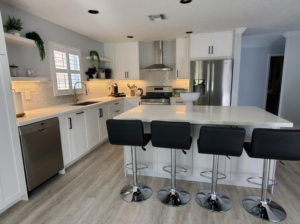 Example of a large transitional l-shaped kitchen pantry design in Miami with shaker cabinets, white cabinets, quartz countertops and an island