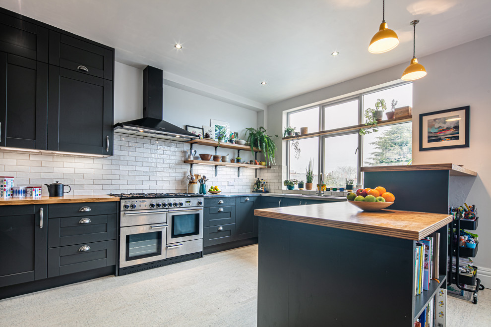 Inspiration for a large industrial eat-in kitchen in Other with shaker cabinets, blue cabinets, stainless steel benchtops, white splashback, subway tile splashback, stainless steel appliances, cork floors, a peninsula and white floor.