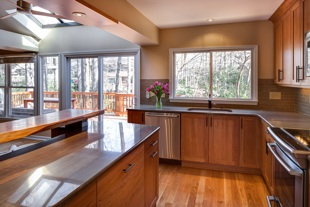 Photo of a small country l-shaped eat-in kitchen in Charlotte with a single-bowl sink, shaker cabinets, medium wood cabinets, granite benchtops, green splashback, ceramic splashback, stainless steel appliances, light hardwood floors and a peninsula.