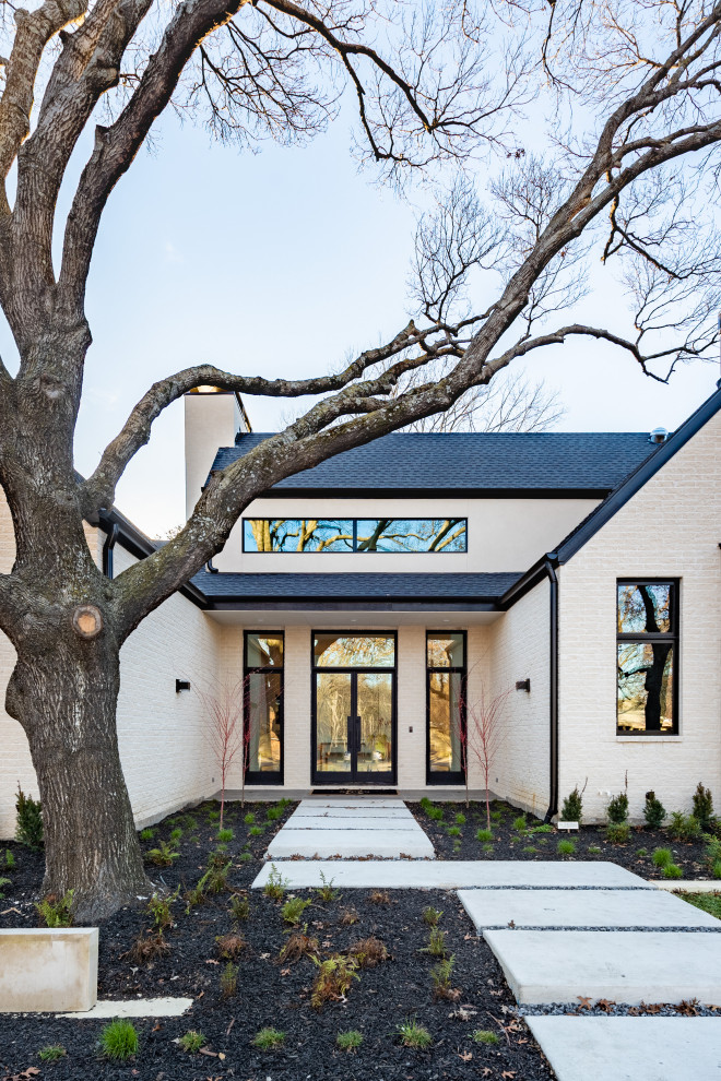 Photo of a large modern two-storey stucco white house exterior in Dallas with a gable roof and a mixed roof.