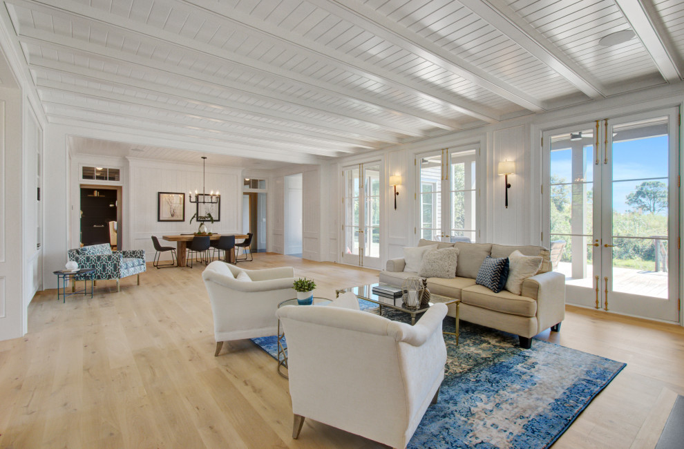 Inspiration for an expansive beach style living room in Charleston with light hardwood floors, a standard fireplace, timber and planked wall panelling.