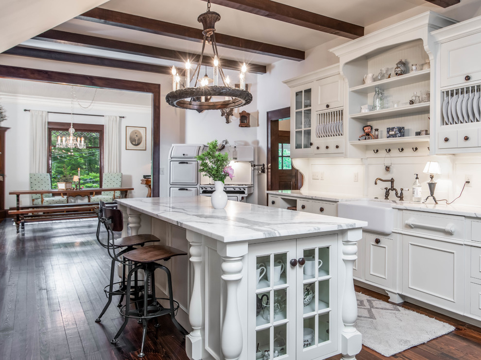Photo of a large country u-shaped separate kitchen in Other with a farmhouse sink, white cabinets, white splashback, dark hardwood floors, with island, brown floor, white benchtop, raised-panel cabinets, quartzite benchtops and panelled appliances.