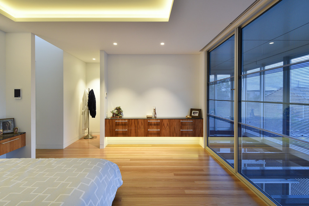 Photo of a large modern master bedroom in Brisbane with white walls, light hardwood floors, no fireplace and brown floor.
