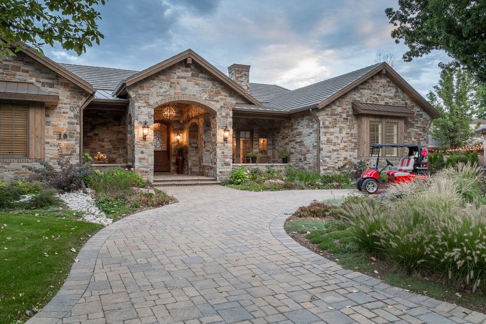 Inspiration for a traditional one-storey house exterior in Denver with stone veneer, a gable roof and a tile roof.
